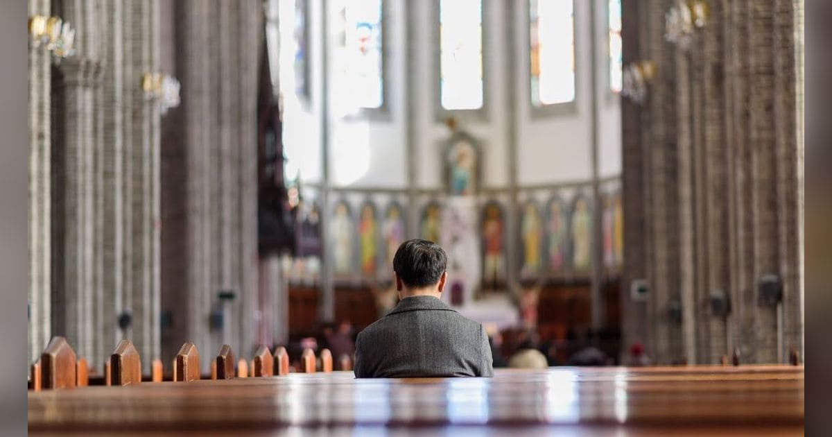 eorang umat Kristen sedang berdoa di dalam gereja sebagai wujud kasih kepada Tuhan