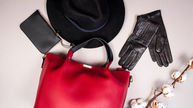 Tas merah elegan dipadukan dengan aksesori seperti topi hitam, sarung tangan kulit, dan dompet hitam untuk tampilan stylish