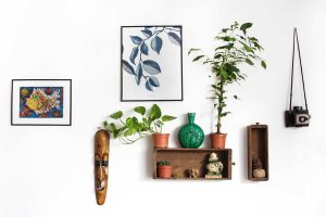 Dekorasi dinding kreatif dengan rak kayu, tanaman hias, dan pajangan artistik untuk tampilan interior estetik