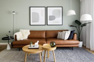 ruang tamu minimalis dengan sofa kulit coklat, pencahayaan alami, dan dekorasi modern yang seimbang