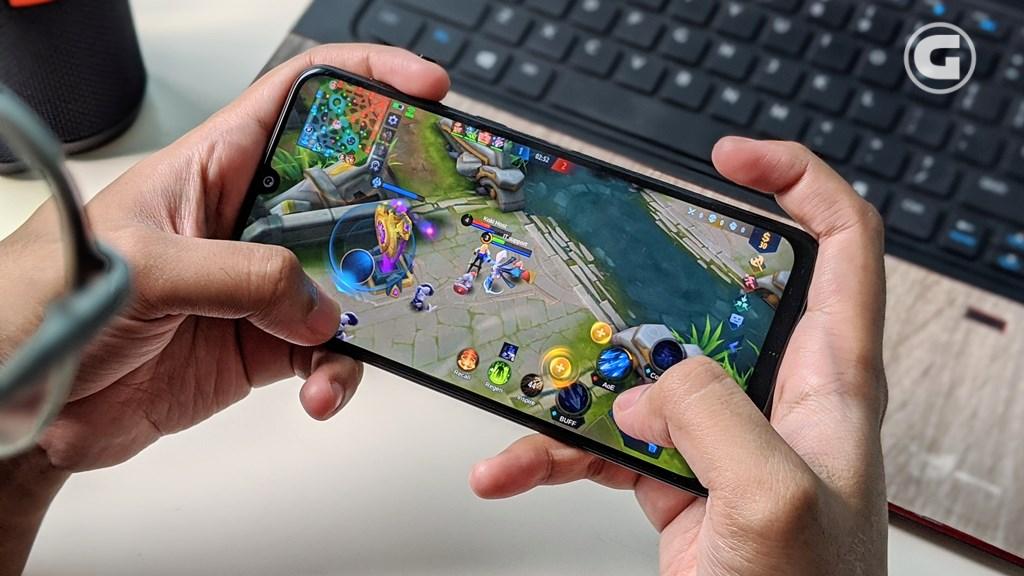 Seorang gamer sedang bermain game MOBA di smartphone, menunjukkan kontrol permainan dan strategi dalam pertandingan."